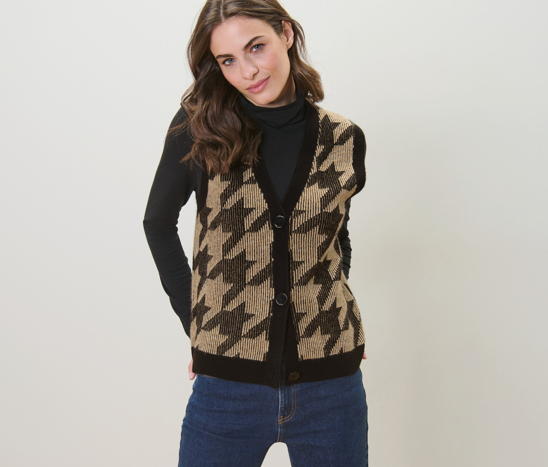 Kobieta pozuje w dzianinowej kamizelce w pepitkę.