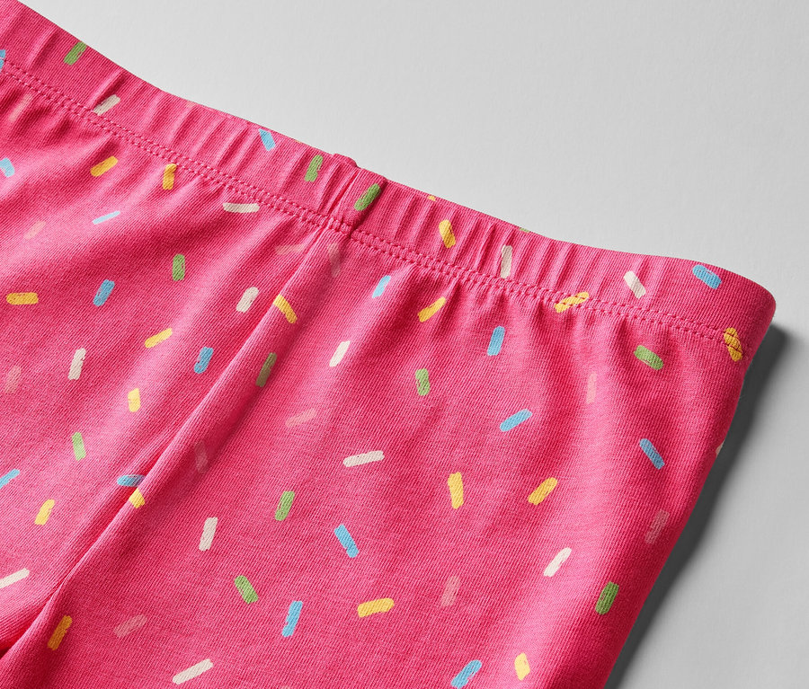Zbliżenie na pas różowych legginsów w kolorowe posypki. Krótkie legginsy, 2 pary, różowe i żółte.