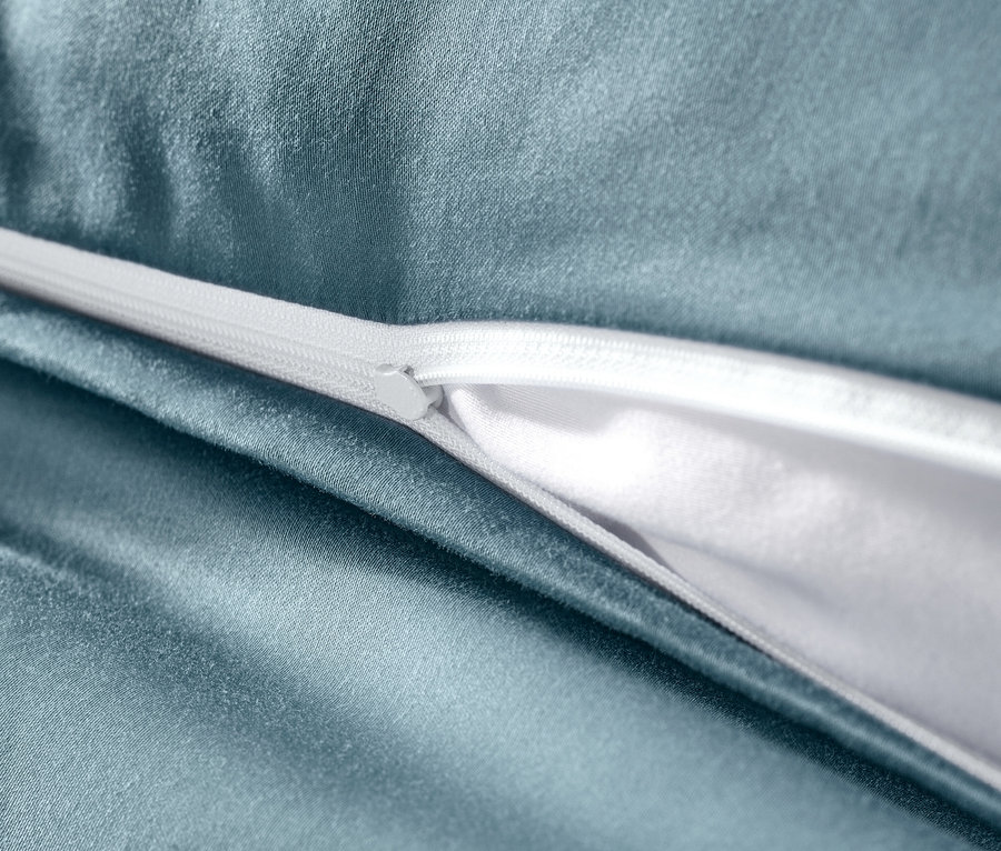 Szczegół niebieskiej pościeli z satyny bawełnianej z białym zamkiem błyskawicznym.