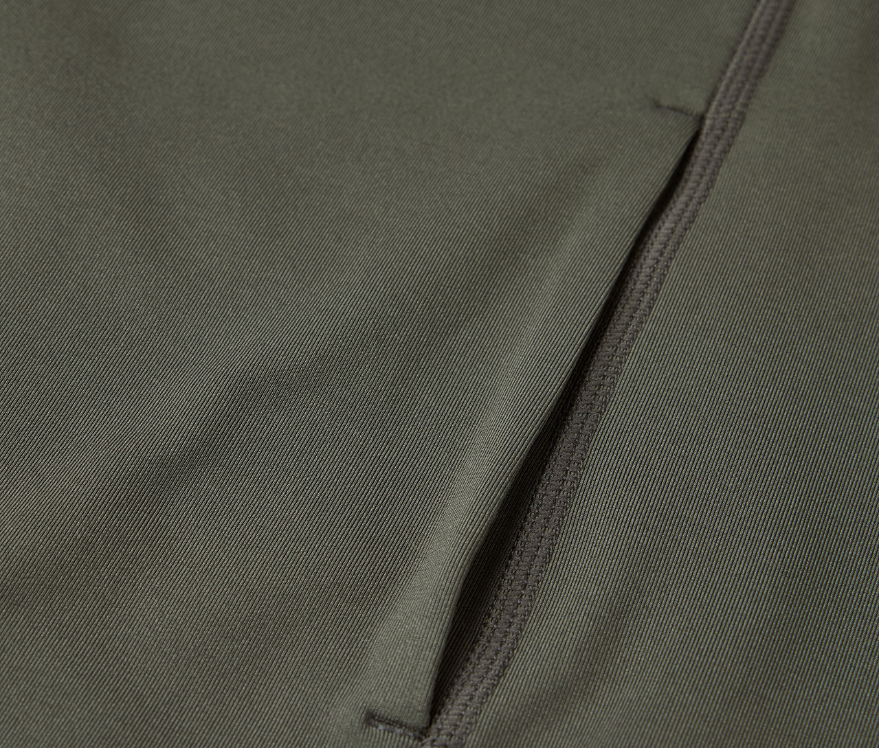 Zbliżenie na oliwkowozieloną tkaninę z kieszenią na zamek błyskawiczny.