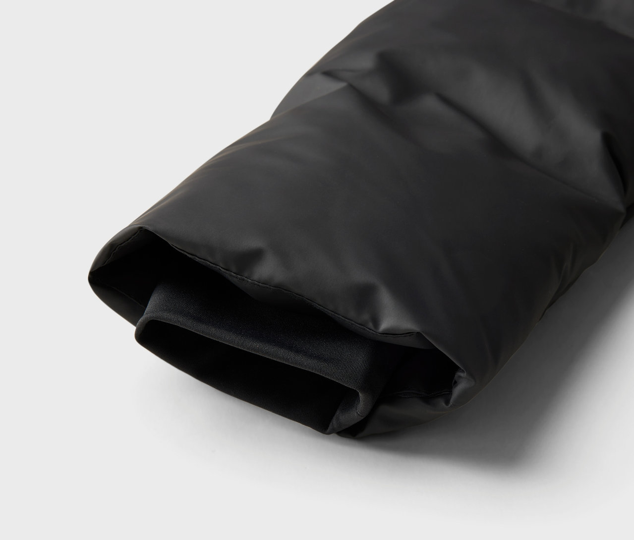 Szczegółowy widok rękawa czarnej kurtki puchowej.