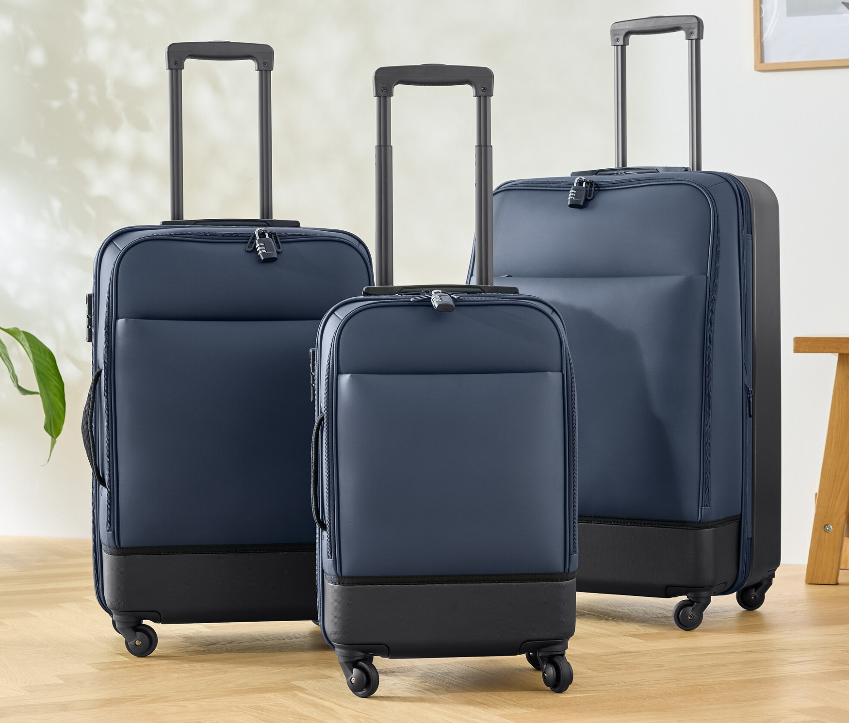 Trzy walizki hybrydowe (mała, średnia i duża) stoją na drewnianej podłodze.