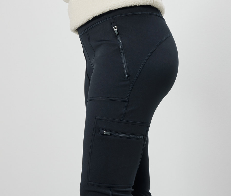 Widok z boku kobiety w czarnych spodniach z kieszeniami zapinanymi na zamek.