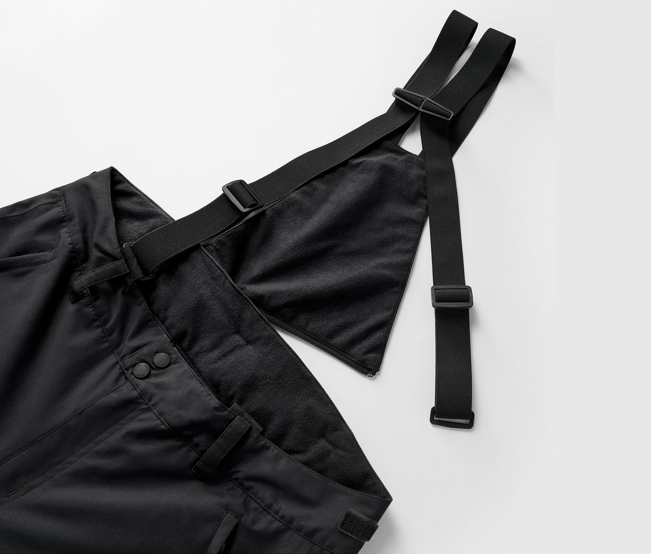 Zbliżenie na czarne spodnie na szelkach z regulowanymi paskami.