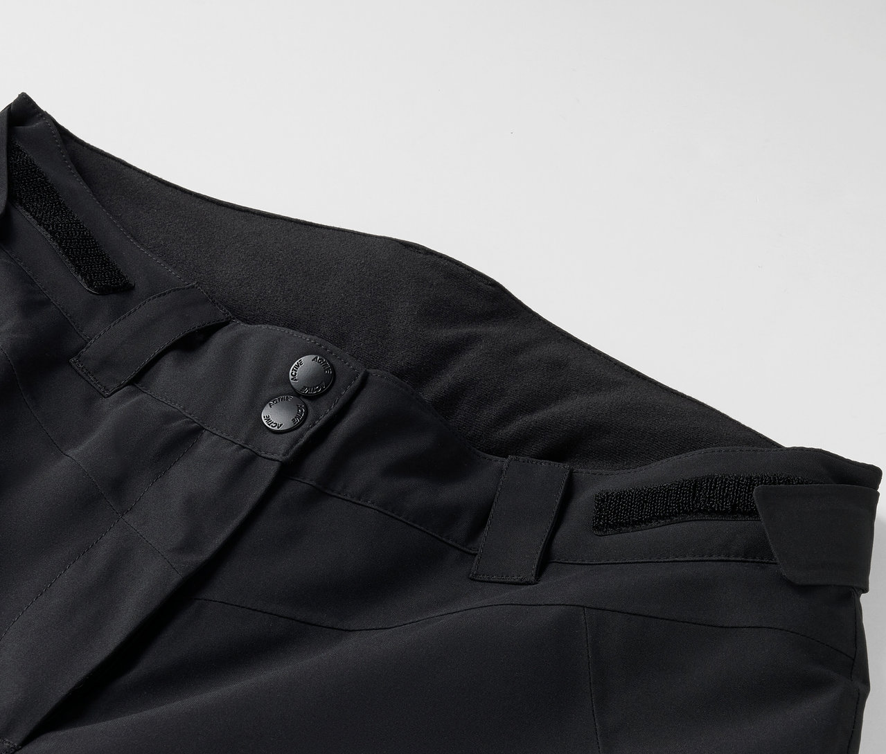 Zbliżenie na czarne spodnie z guzikami i szlufkami.