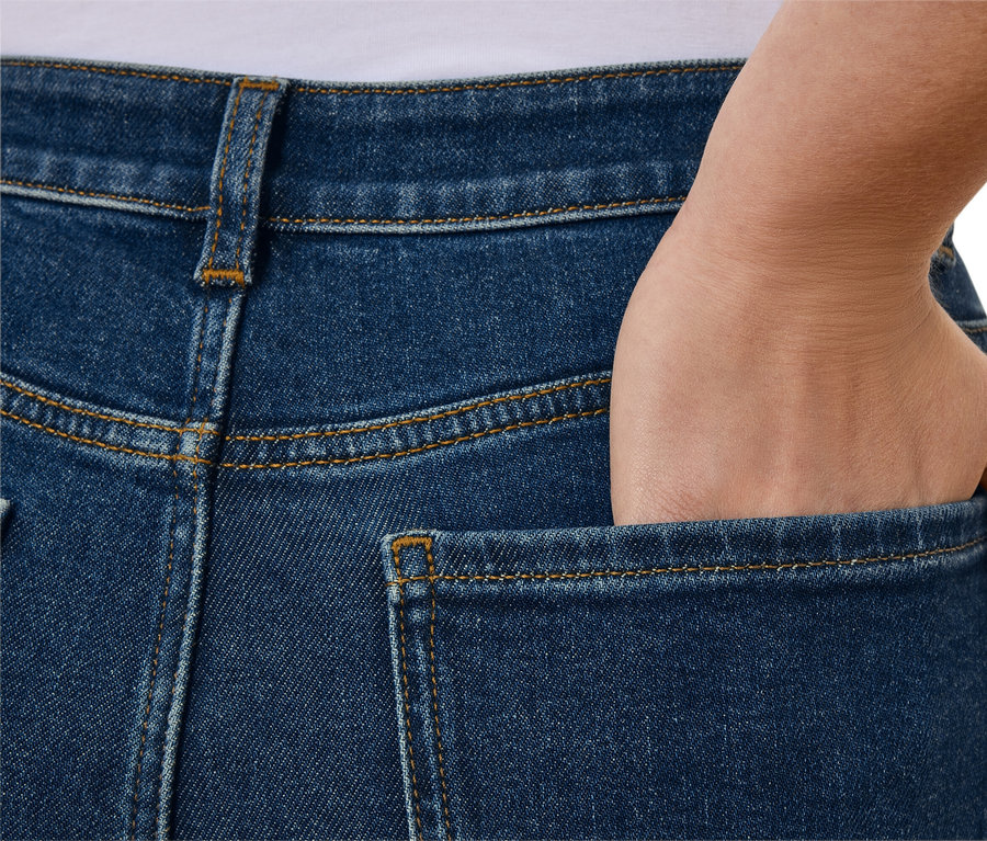 Zbliżenie na tył niebieskich dżinsów z ręką w kieszeni.