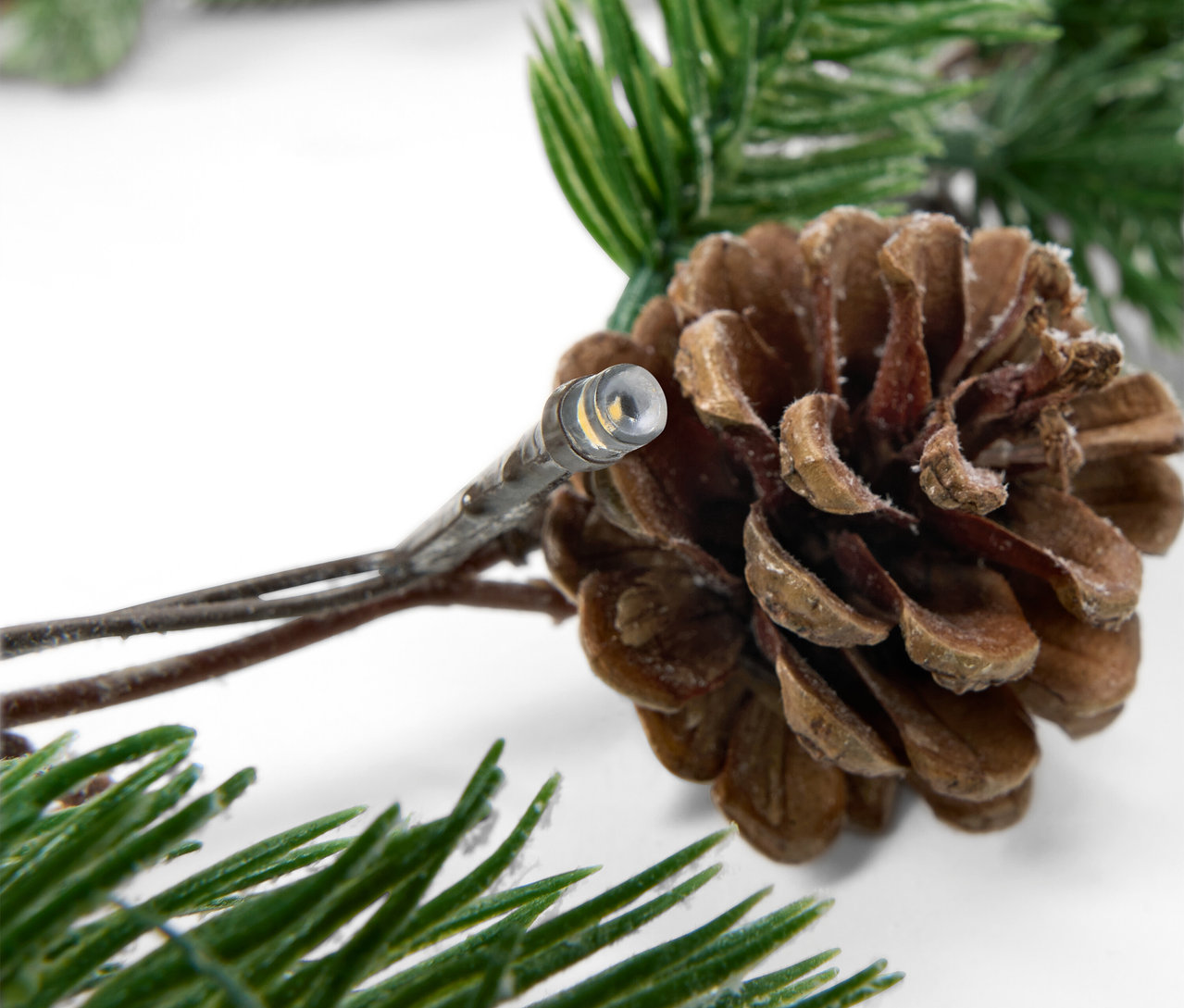 Szczegół łańcucha światełek ze szyszką i gałązkami jodły.