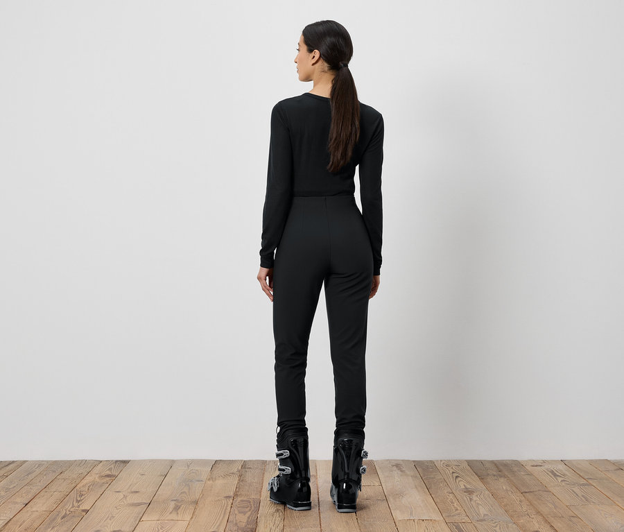 Kobieta w czarnym stroju narciarskim stoi tyłem.