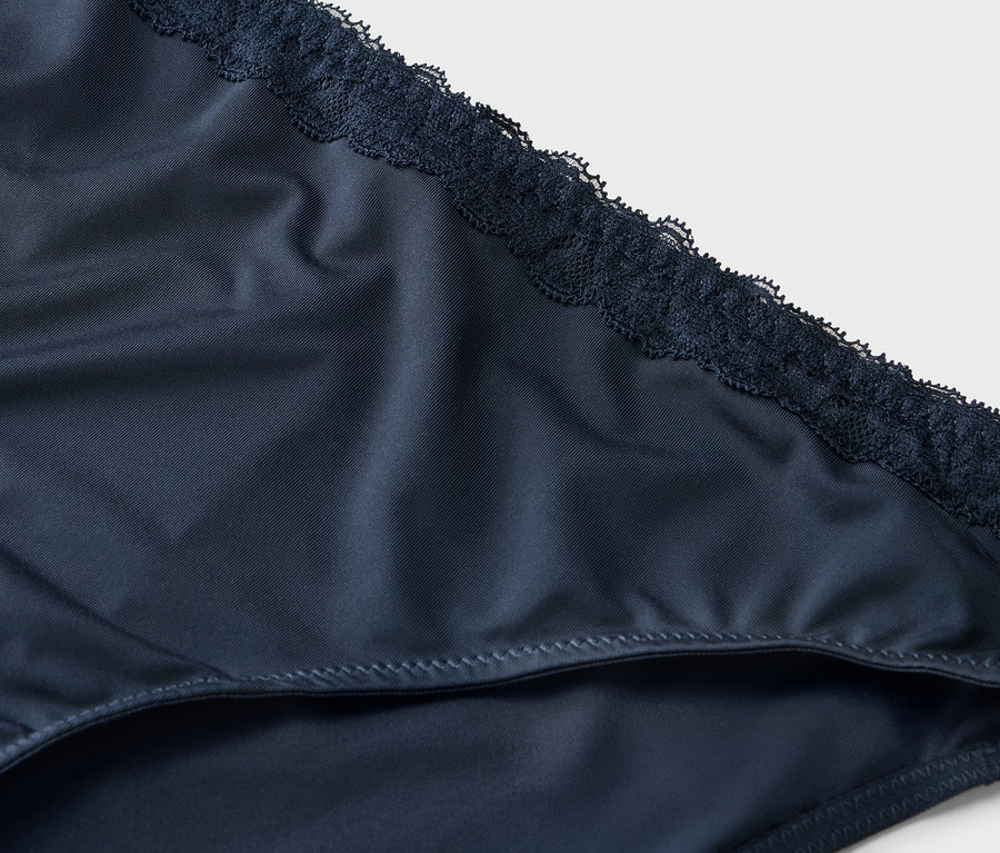 Zdjęcie z bliska granatowych damskich majtek wykończonych koronką.