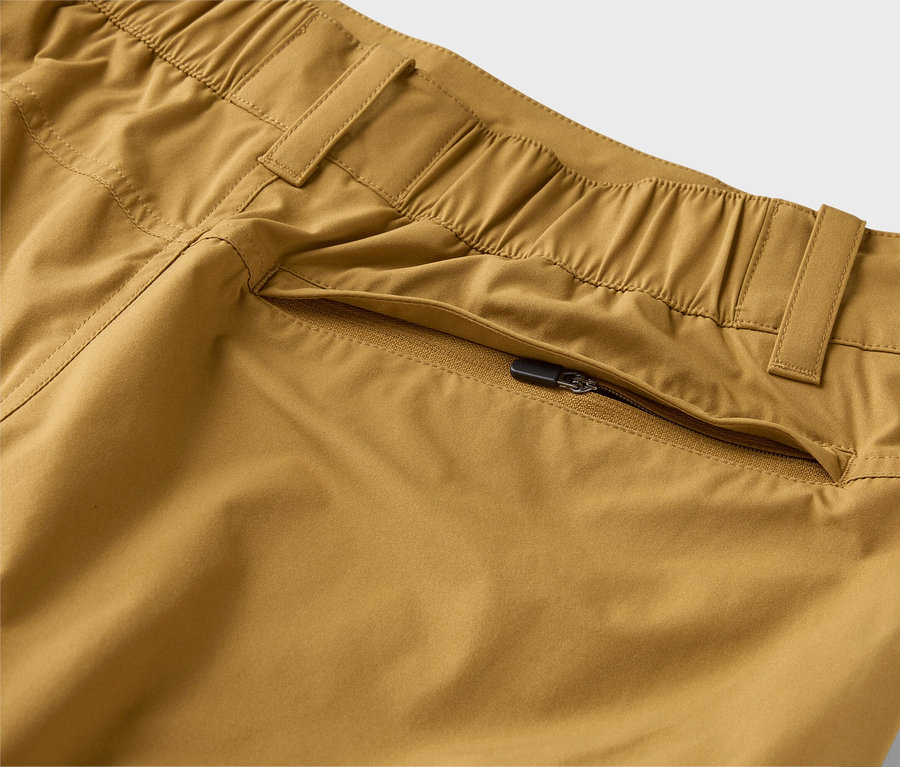 Szczegółowe ujęcie khaki spodni z elastycznym pasem i kieszenią na zamek błyskawiczny.
