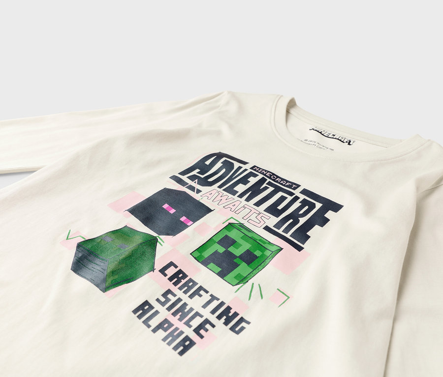 Na białej koszuli z długim rękawem znajduje się grafika z Minecrafta z napisem "Adventure Awaits" i "Crafting Since Alpha".