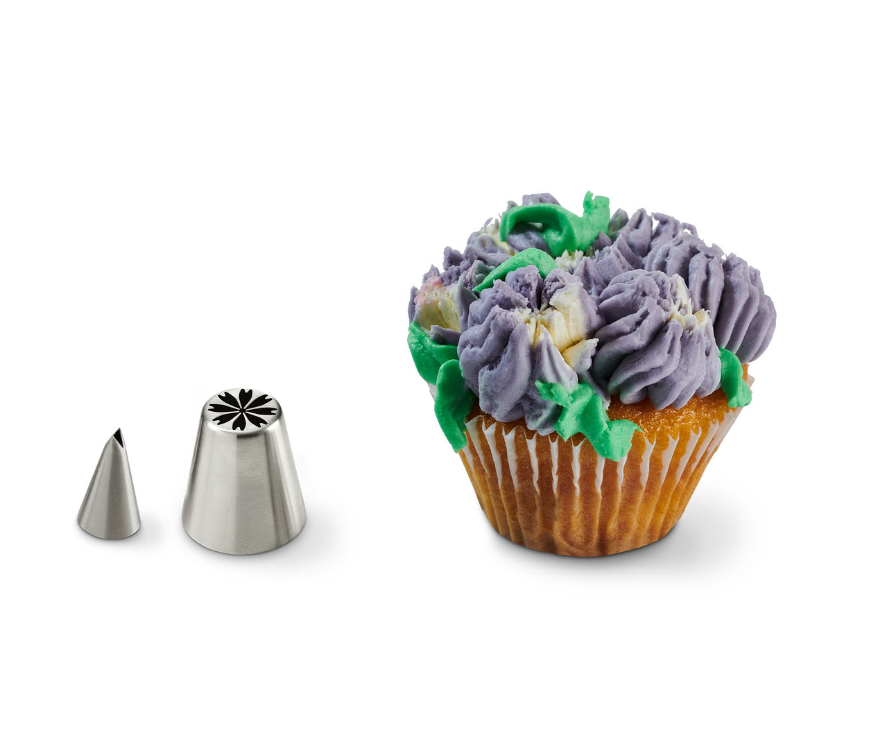 Dwie metalowe końcówki do dekorowania ciast obok ozdobionego babeczki. Zestaw do dekorowania ciast z wieloma końcówkami.