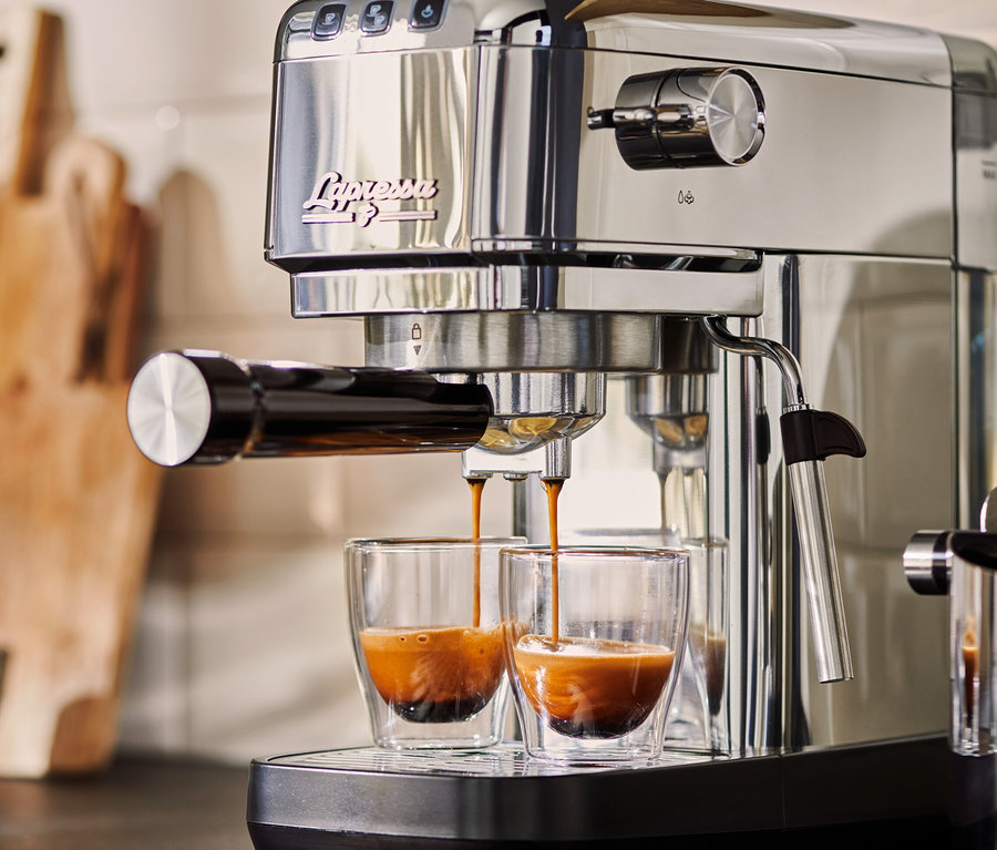 Srebrny ekspres kolbowy do kawy »Lapressa« przygotowuje espresso do dwóch szklanych filiżanek.