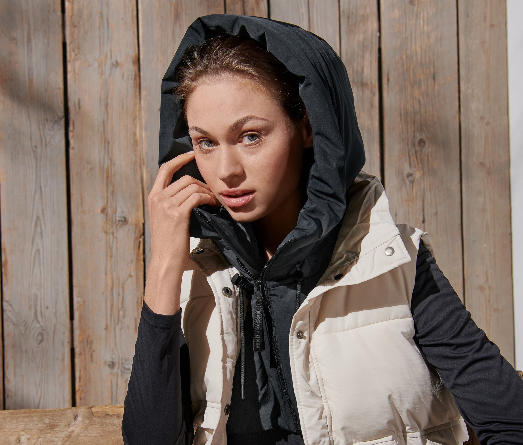 Kobieta ma na sobie watowany kaptur ze stójką i kamizelkę.