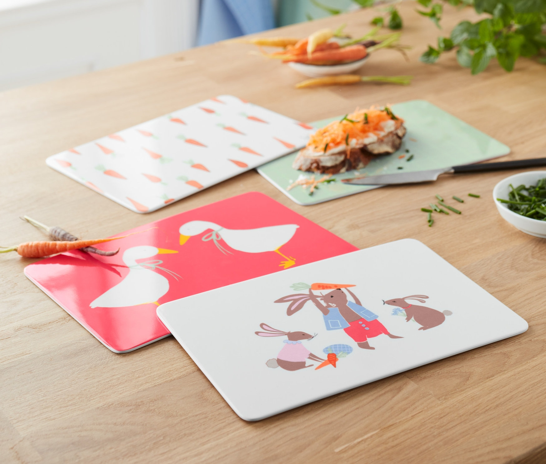 Cztery deski do krojenia leżą na drewnianym stole.