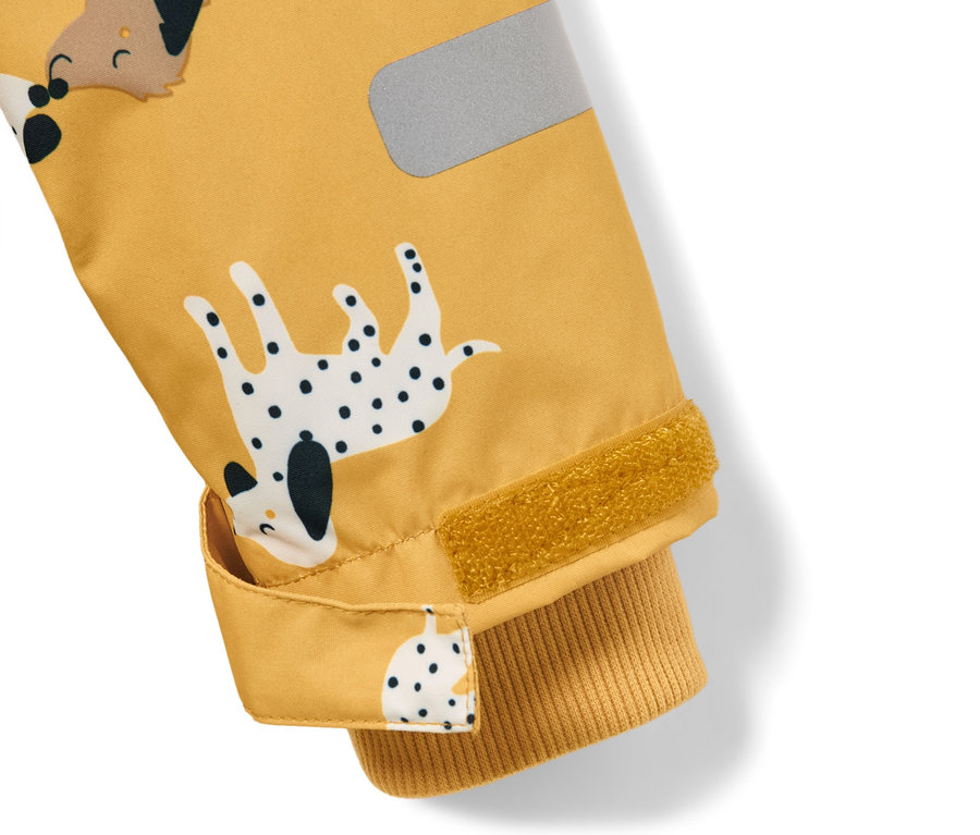 Zbliżenie na żółty kombinezon przeciwdeszczowy z nadrukiem psów i odblaskowym paskiem.