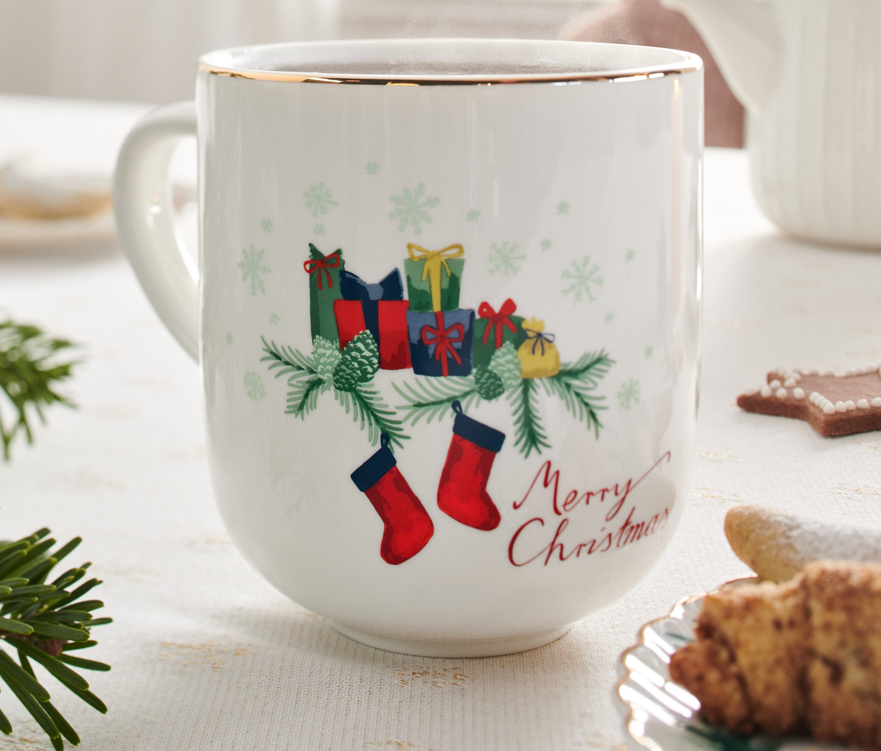 Zbliżenie na duży kubek ze złotym błyszczącym zdobieniem o tematyce świątecznej na świątecznie nakrytym stole.