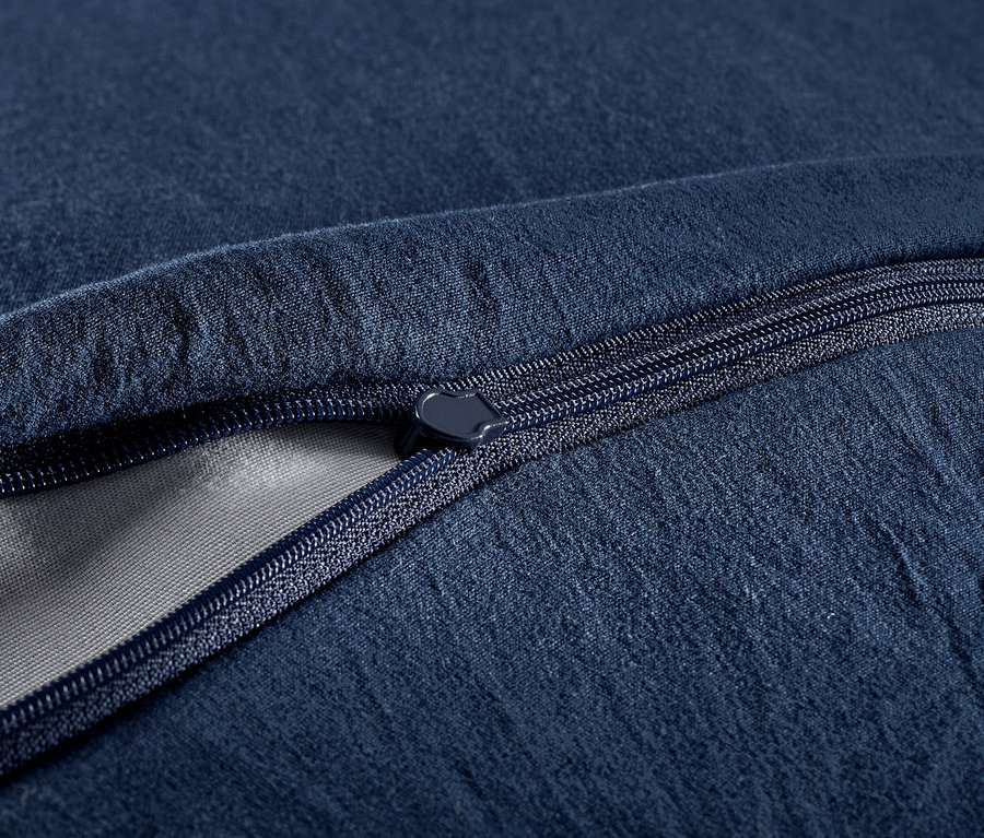 Zbliżenie granatowej pościeli z pikowanym wzorem i zamkiem błyskawicznym.