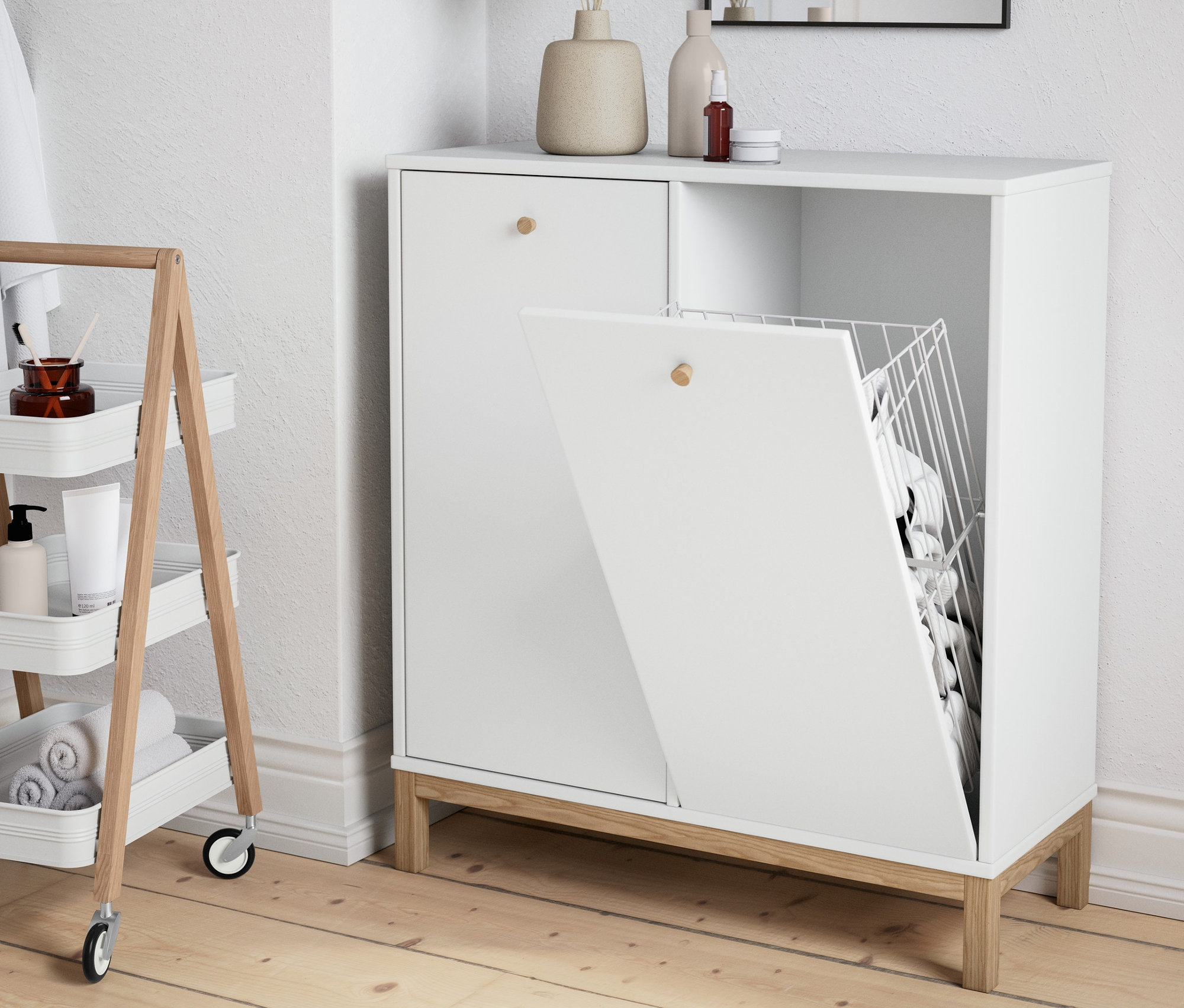 W łazience stoi szafka z koszami na pranie i półka na kółkach.