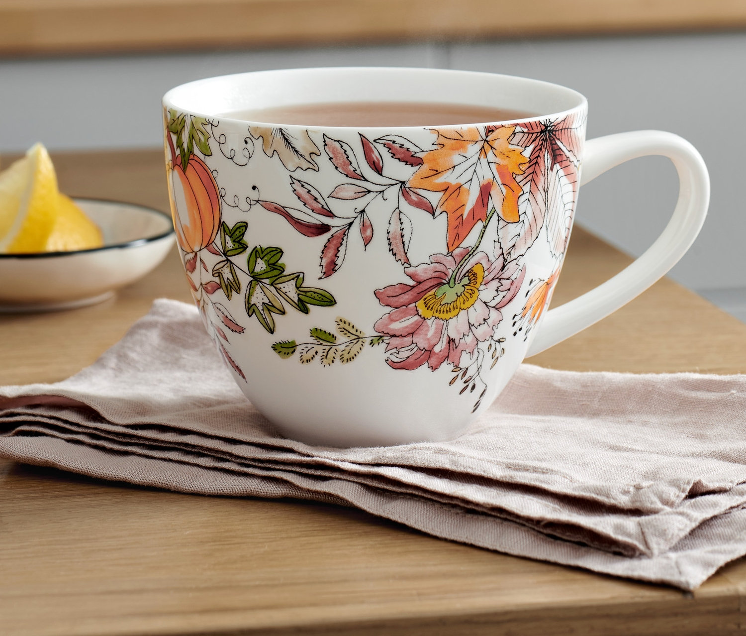 Filiżanka XL z jesiennym wzorem kwiatowym na stole z cytryną.