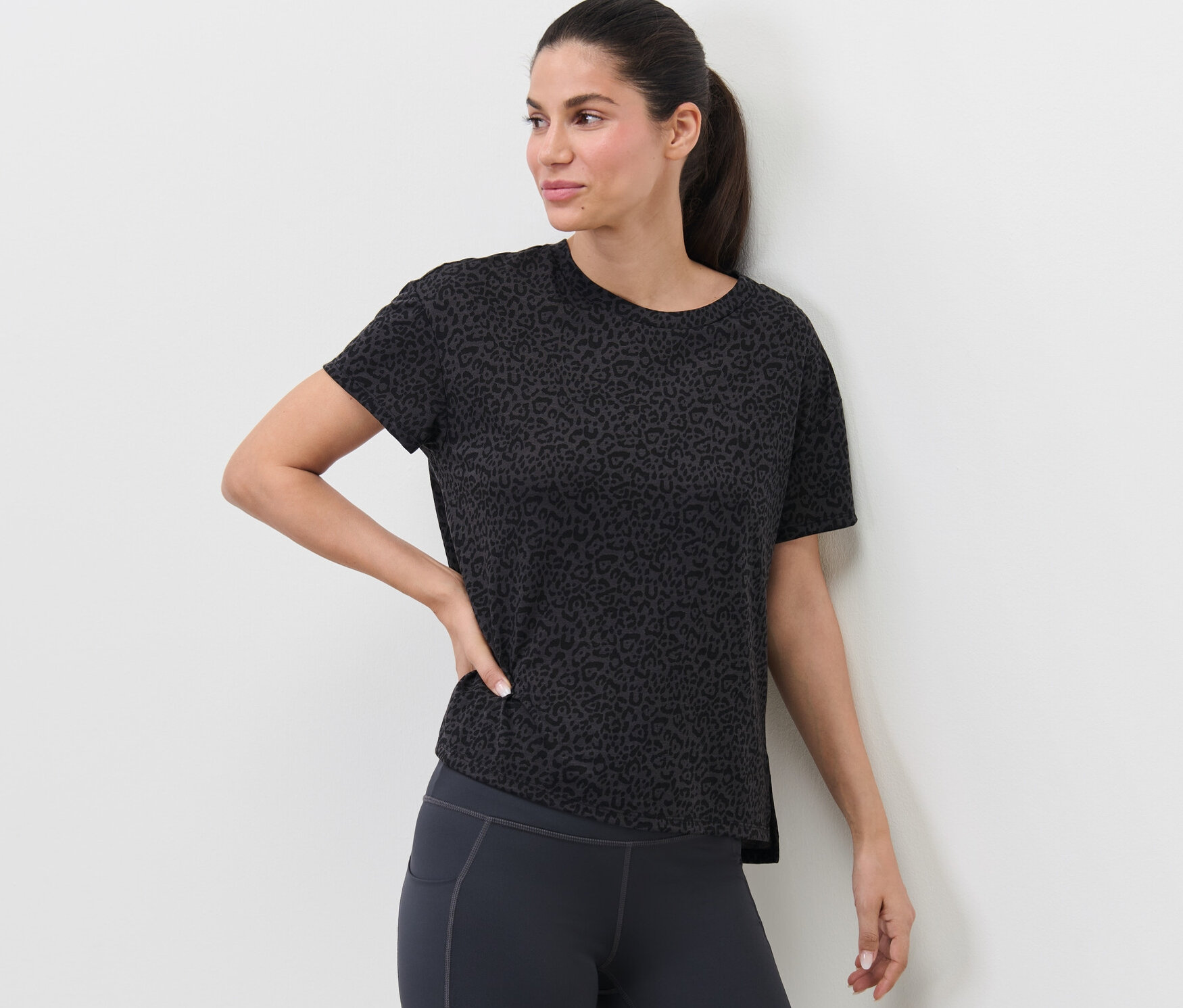 Kobieta pozuje w antracytowej koszulce sportowej.