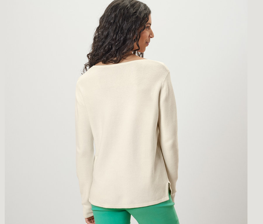 Kobieta od tyłu ma na sobie kremowy sweter.