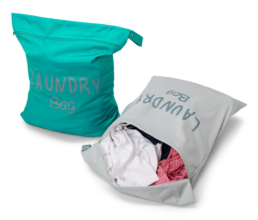 Dwie torby podróżne na pranie: turkusowa i szara z ubraniami.