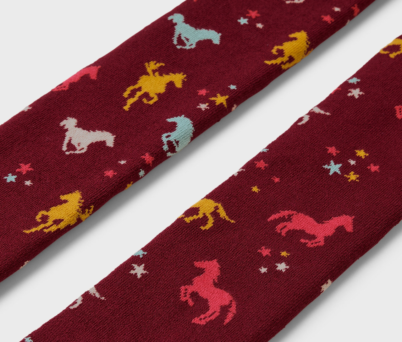 Szczegółowy widok dwóch dziecięcych rajstop termicznych we wzory koni i gwiazd.