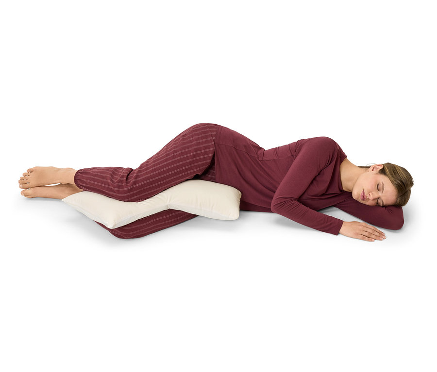 Kobieta leży na boku i obejmuje poduszkę.