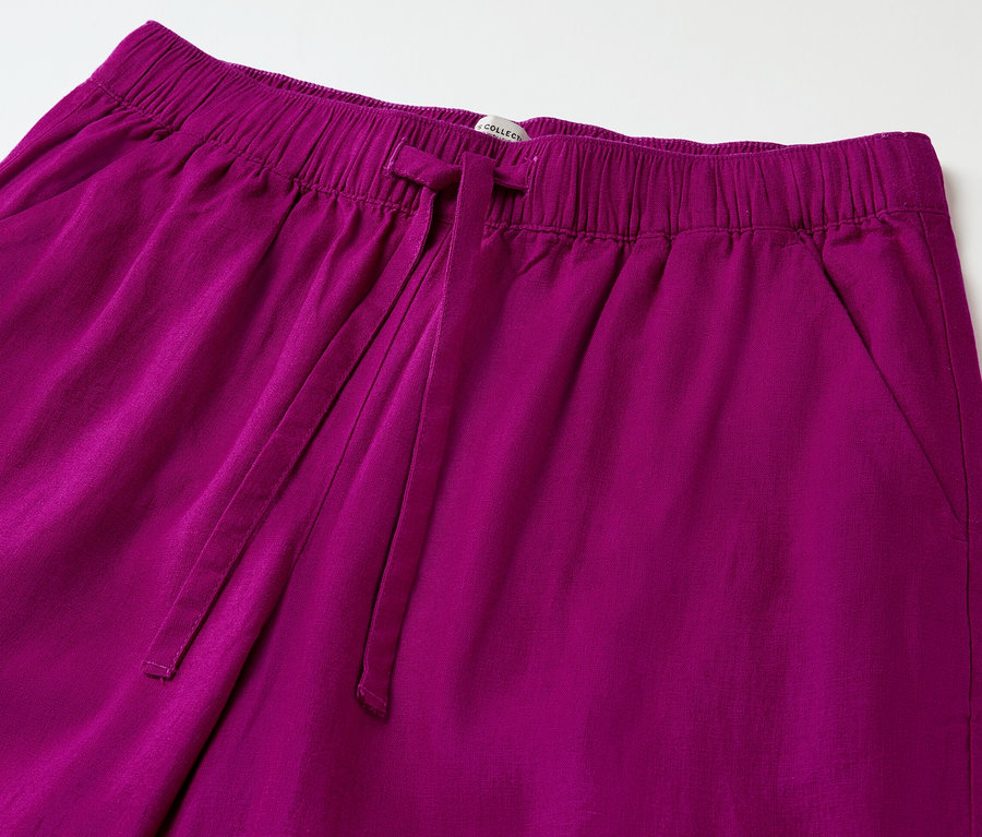 Zbliżenie na lniane spodnie jagodowe z elastyczną talią i sznurkiem.