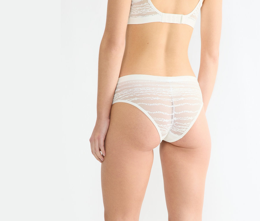 Kobieta od tyłu w figach sloggi Free Evolve Hipster Lace w kolorze jedwabnej bieli i pasującym biustonoszu.