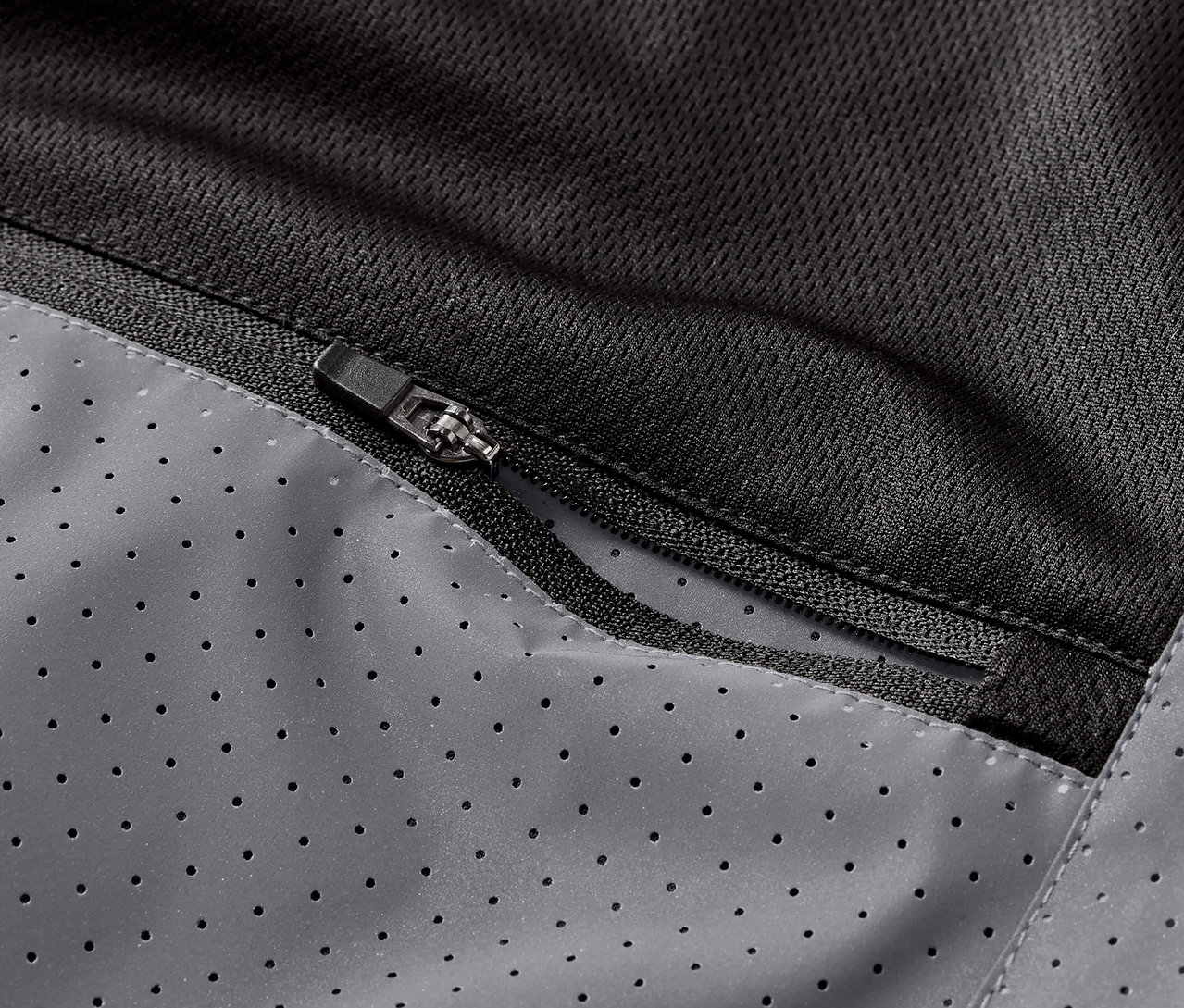 Zbliżenie na kieszeń zapinaną na zamek w kamizelce odblaskowej do biegania.