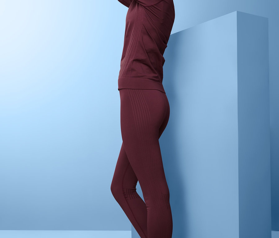 Kobieta pozuje w bordowej, bezszwowej bieliźnie funkcyjnej.