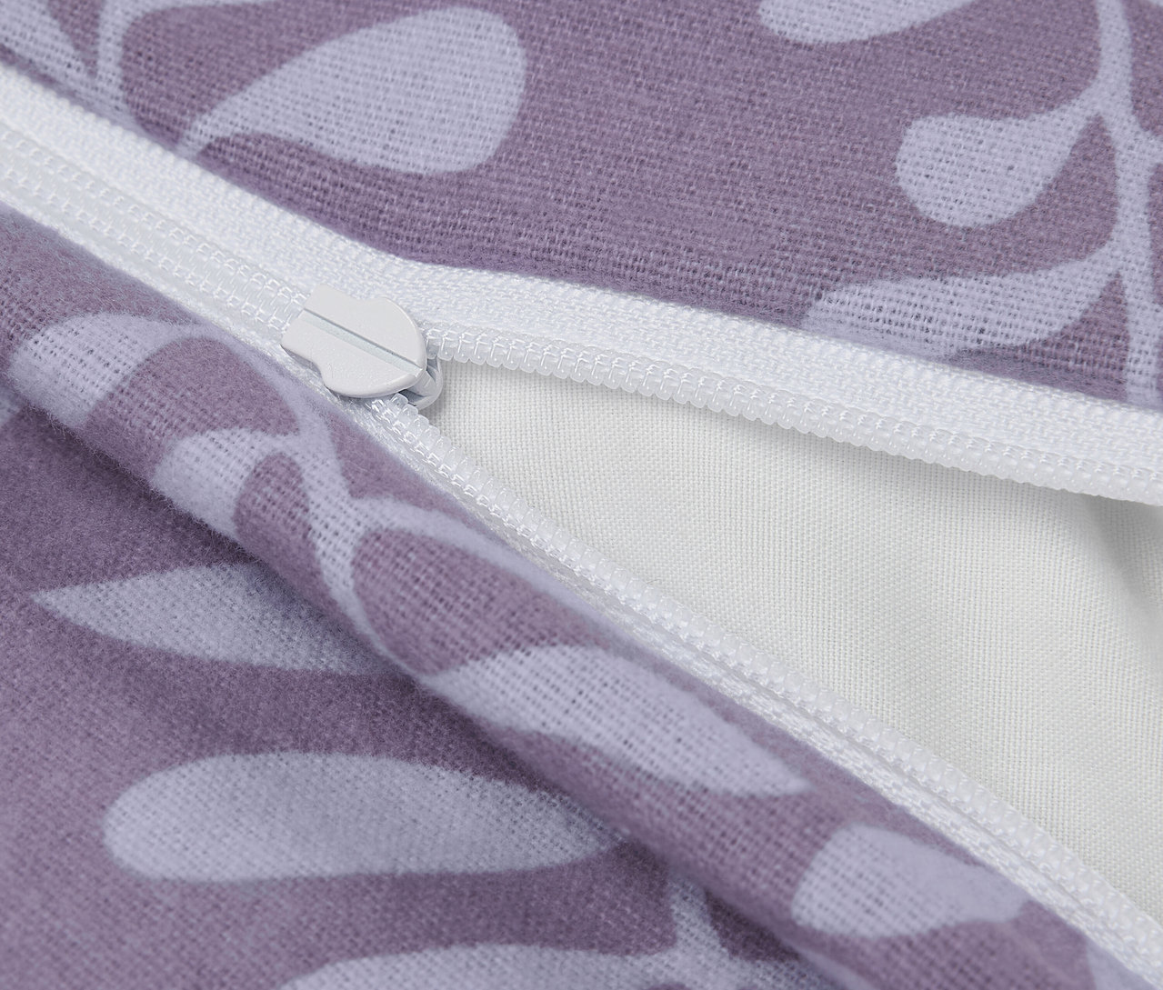 Zbliżenie fioletowej poszewki na poduszkę z białymi liśćmi i zamkiem błyskawicznym.