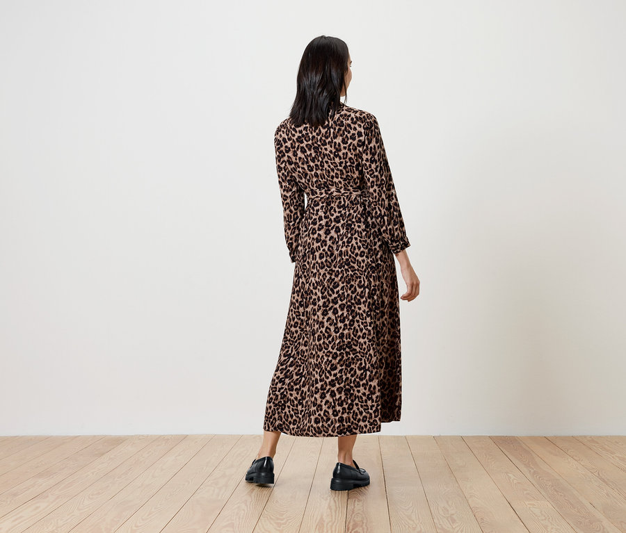 Kobieta w długiej sukience w zwierzęcy wzór, tyłem do kamery.