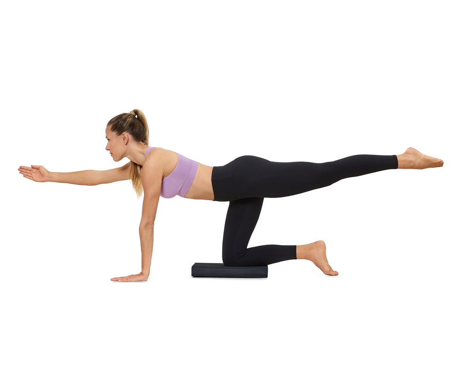 Kobieta ćwiczy jogę na macie, ubrana w odzież sportową.