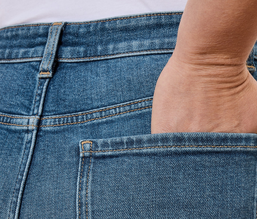Ręka w tylnej kieszeni niebieskich dżinsów.