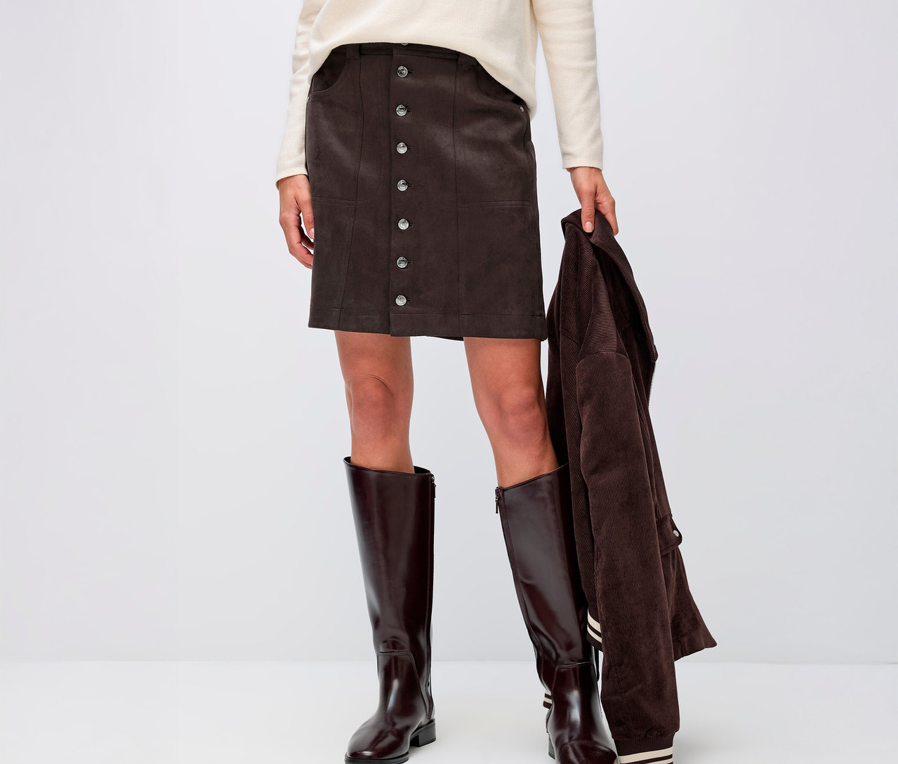 Kobieta ma na sobie welurową spódnicę Street One, kremową górę i brązowe buty.