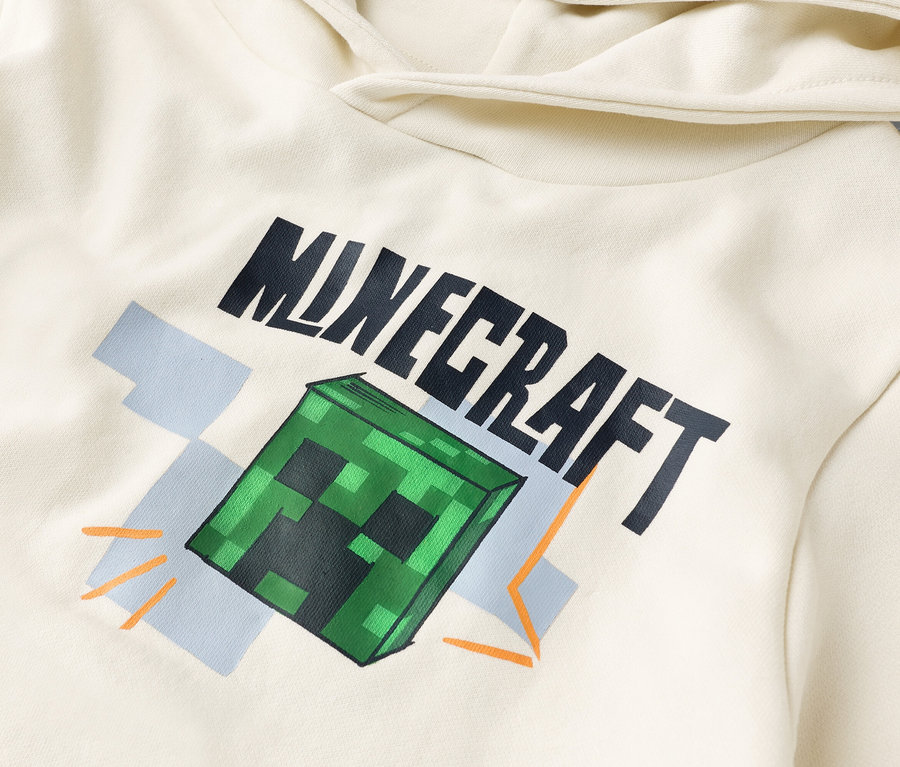 Szczegółowy widok kremowej bluzy z kapturem z nadrukiem "Minecraft" i zielonym blokiem Creeper.