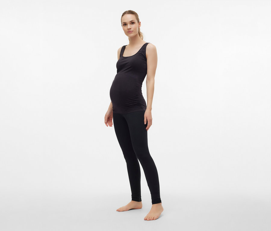 Kobieta w ciąży ma na sobie czarny top MAMALICIOUS „MLHEAL” w rozmiarze uniwersalnym i legginsy.