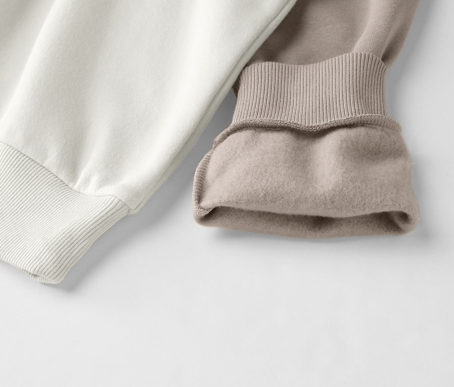 Zbliżenie dwukolorowej bluzy w kolorze białym i beżowym ze ściągaczami.