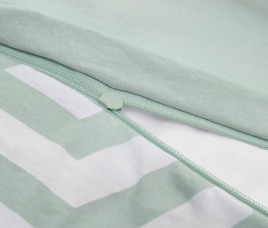 Zbliżenie na jasnozieloną poszewkę na poduszkę w paski z zamkiem błyskawicznym.