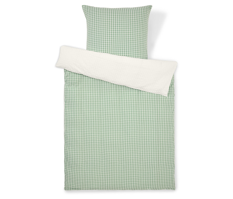 Zestaw pościeli w zielono-białą kratę z białą poszewką na poduszkę, sfotografowany z góry.
