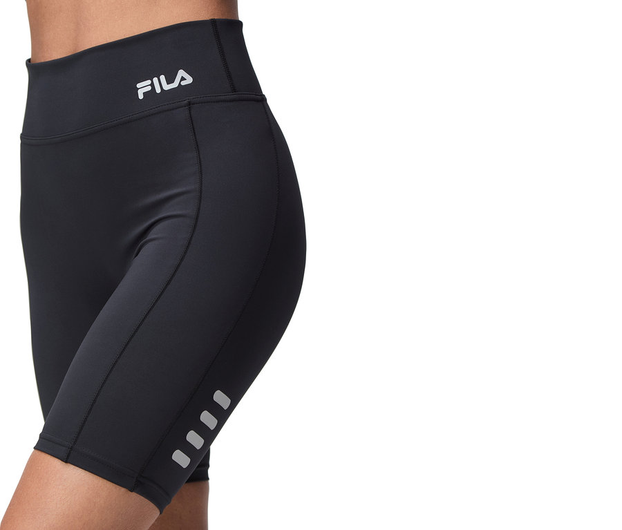 Zbliżenie na osobę ubraną w czarne spodenki rowerowe Fila, z logo Fila na pasie i odblaskowymi detalami na nogawkach.