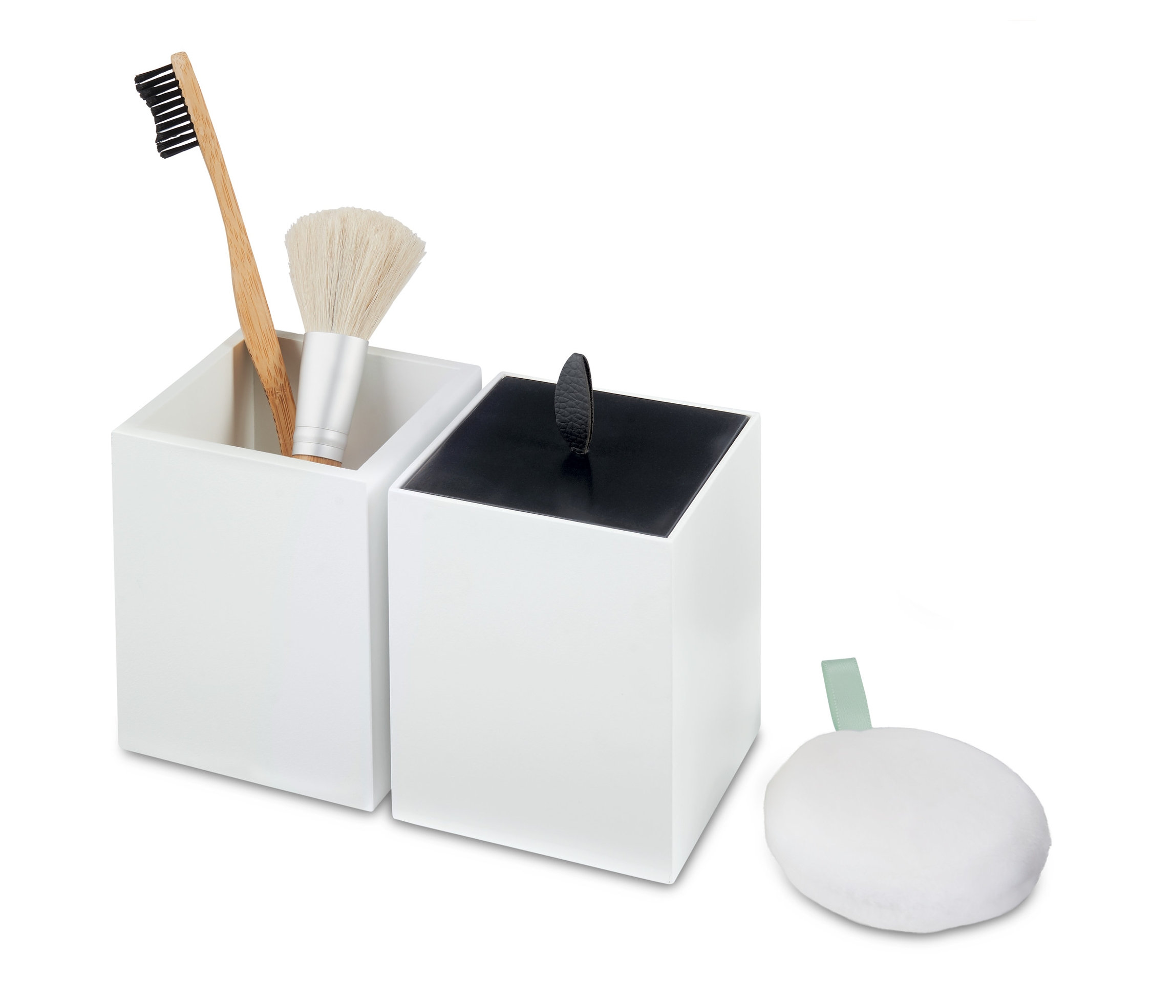 Dwa białe organizery, w jednym szczoteczka do zębów i pędzel do makijażu, obok biała gąbka.