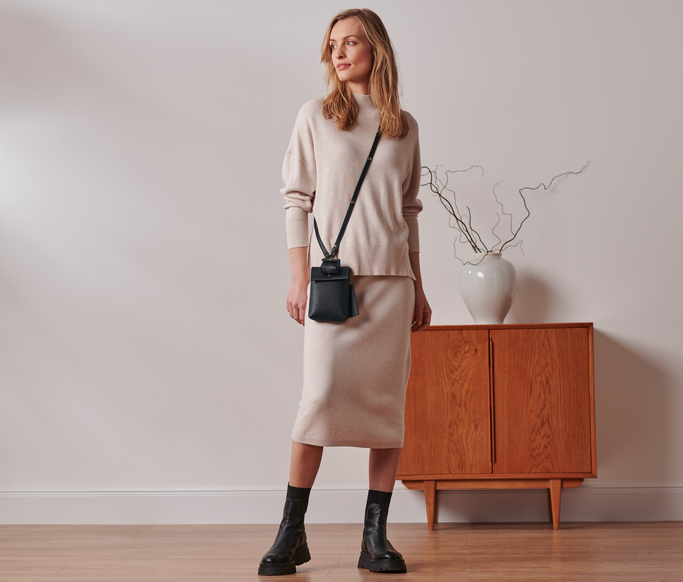 Kobieta stoi w pokoju i ma na sobie mini torebkę.