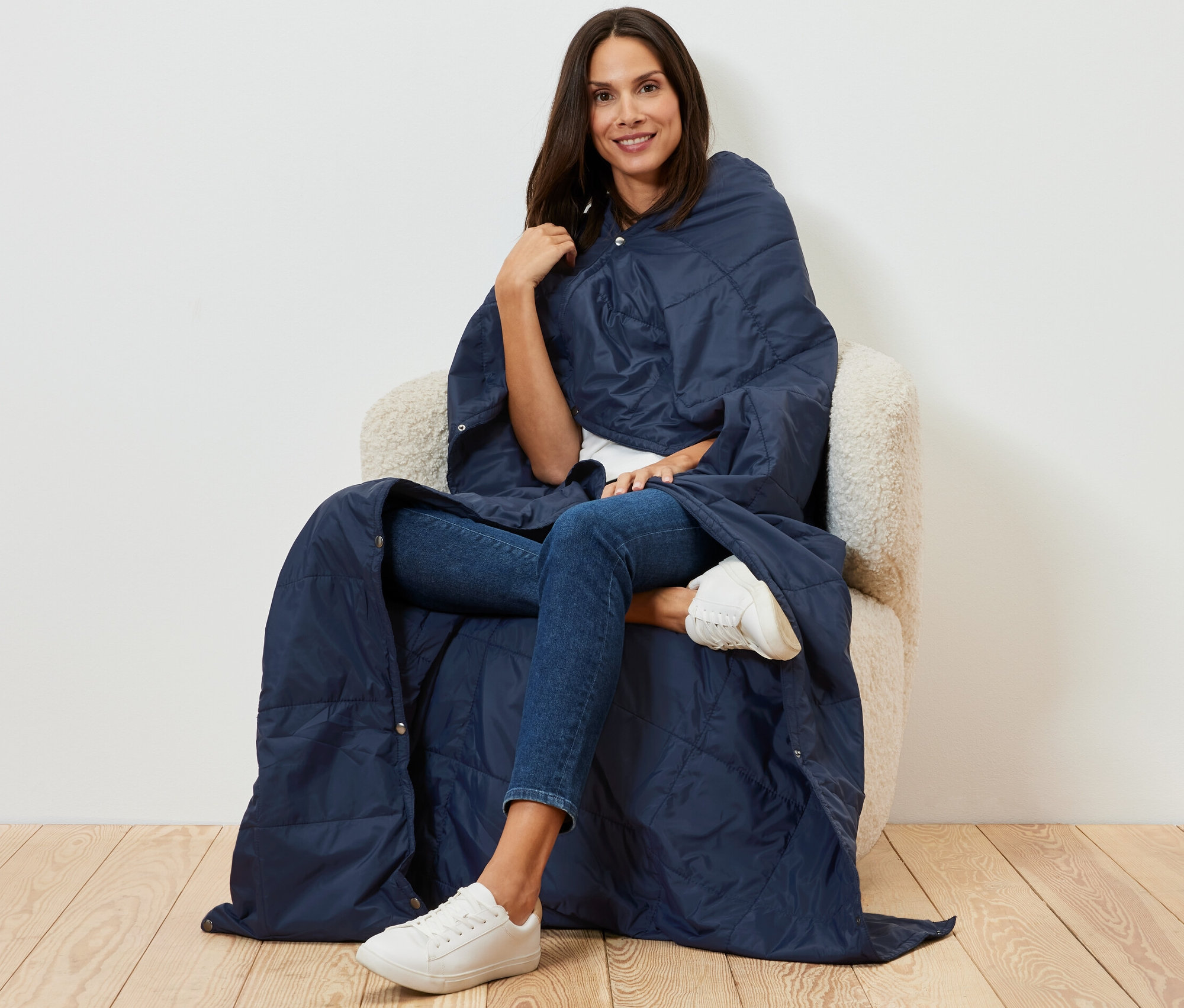 Kobieta siedzi w fotelu, owinięta wyjątkowo lekkim kocem podróżnym.