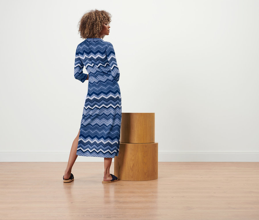 Kobieta stoi tyłem do kamery i ma na sobie sukienkę z dzianiny.