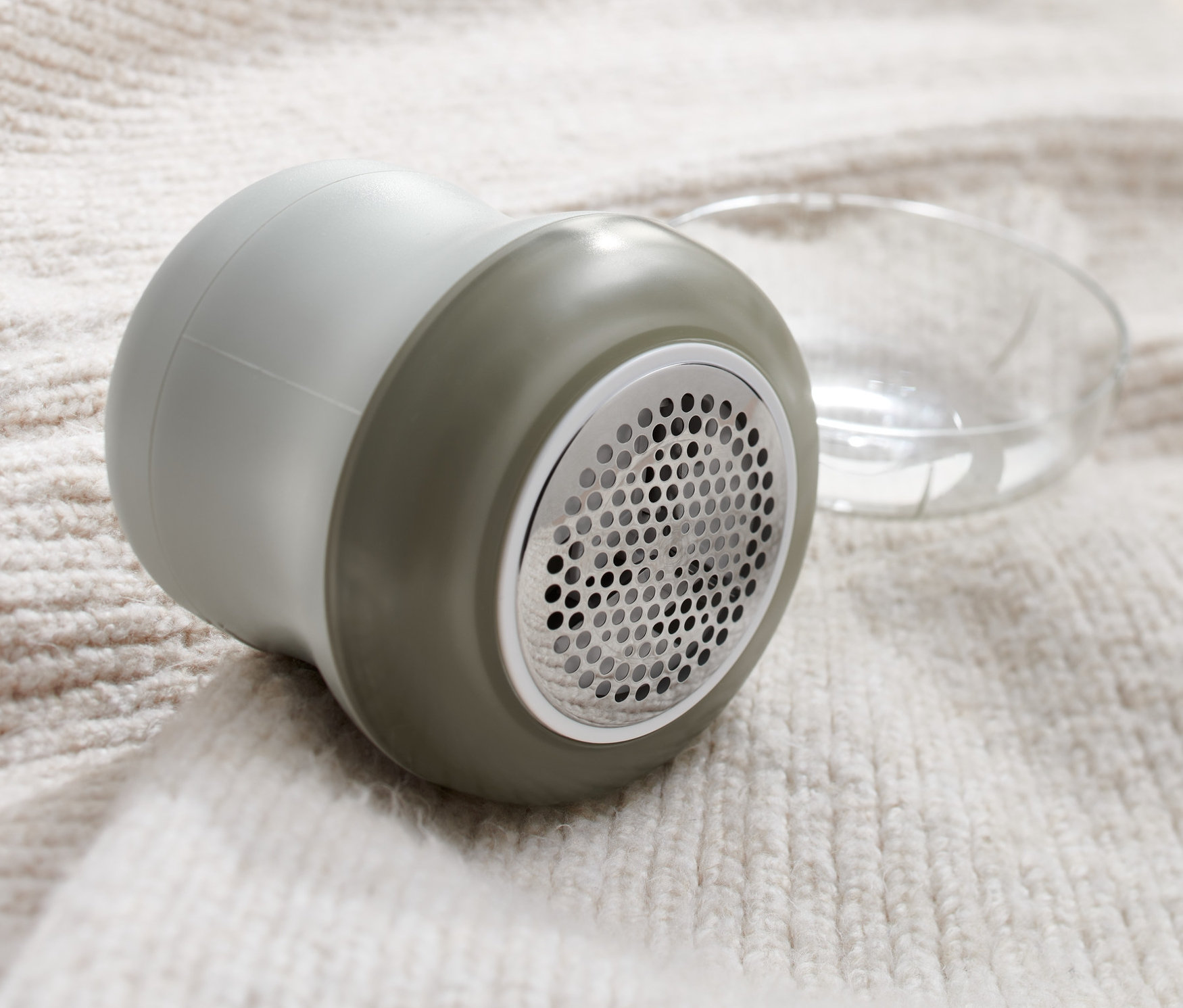 Szara golarka do odzieży leży na swetrze.