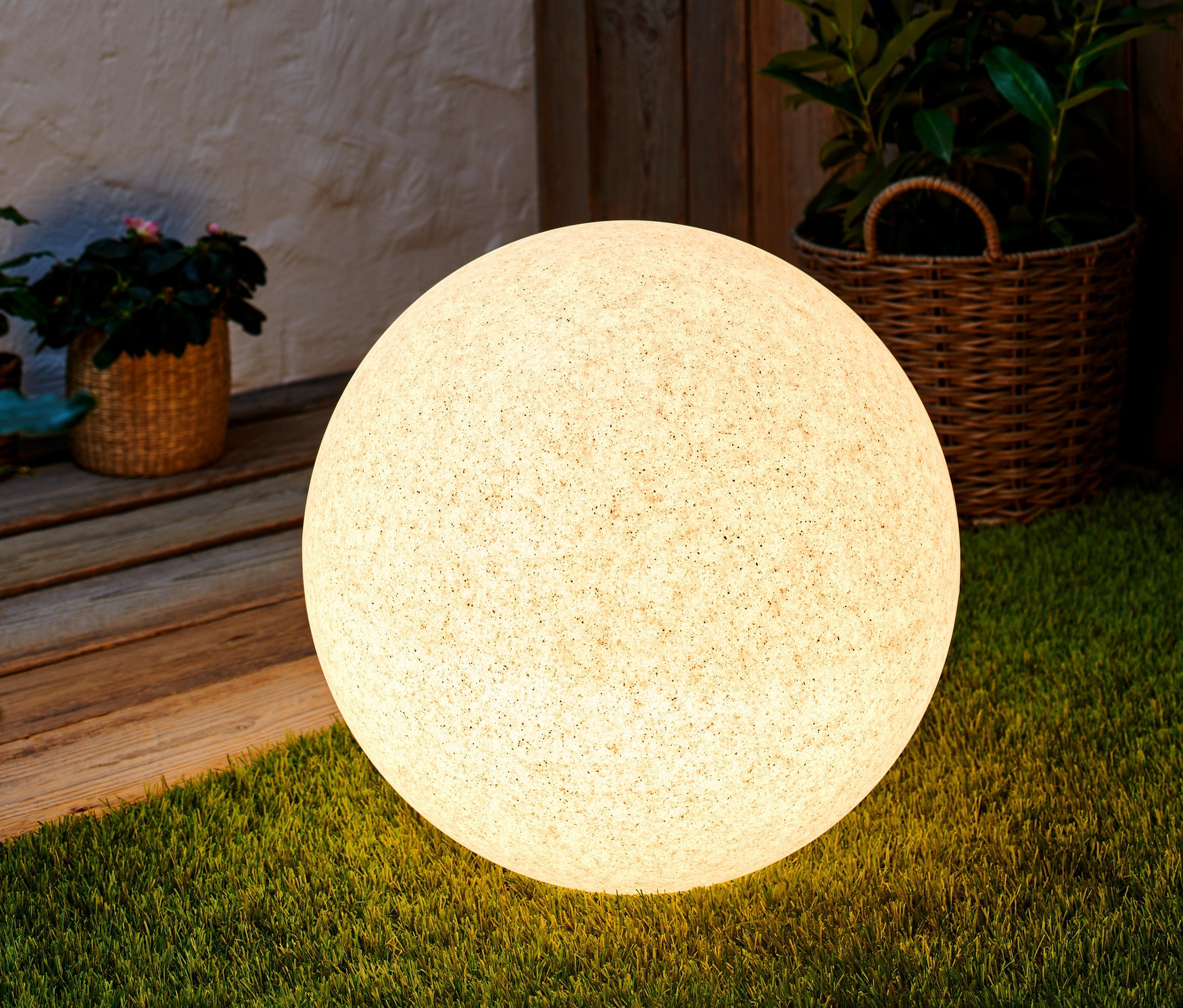 Lampa w kształcie kuli zmieniająca kolory, o średnicy ok. 45 cm, stoi na trawie.